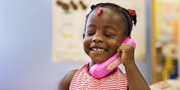 Child holding toy telephone.